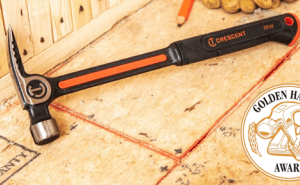 Crescent 22 oz steel framing hammer sitting on a plywood floor with work gloves in the back ground with the Golden Hammer Award winner logo