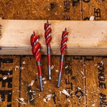 Three Crescent high speed auger wood drill bits laying between a framed wall