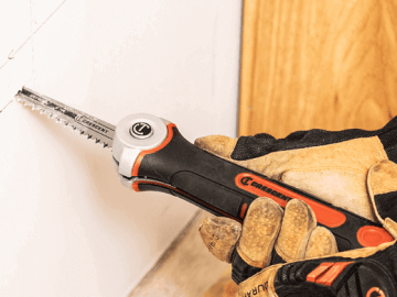 Man using a Crescent jab saw to cut out a spot of dry wall